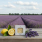 Bar of castile soap on a wooden table in a lavender field with lemons and lavender