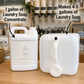 Two white plastic jugs for laundry soap concentrate displayed on a wooden counter in a shop setting, with text overlays explaining the conversion ratio: '1 gallon of Laundry Soap Concentrate' and 'Makes 4-5 gallons of Laundry Soap'.