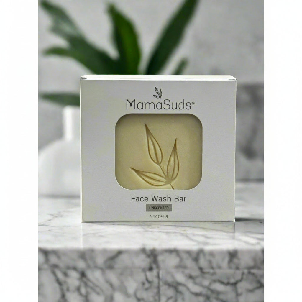 Mamasuds face wash bar packaging on a marble surface with a plant in the background